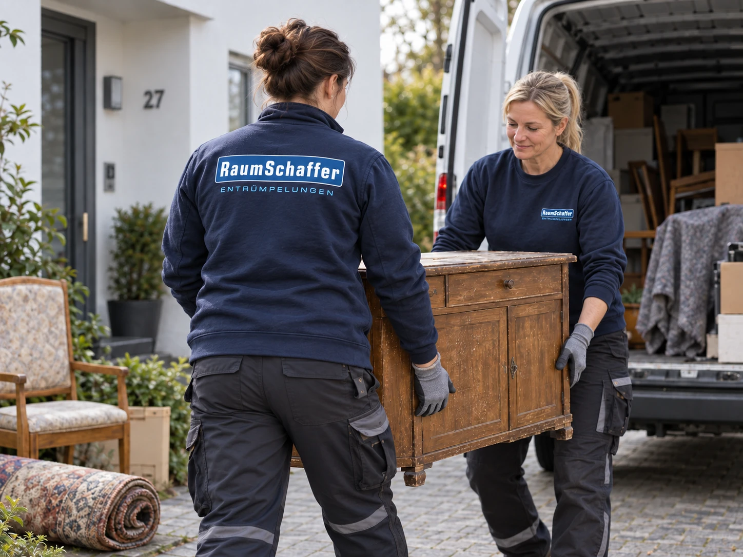 Zwei RaumSchaffer-Mitarbeiterinnen tragen eine alte Kommode zum Transporter